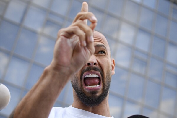 Andrew Tate speaks to media outside the Bucharest Tribunal after being placed under house arrest, in Bucharest, Romania, Aug. 22, 2024. (AP Photo/Alexandru Dobre, File)
