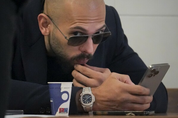 Andrew Tate checks his mobile phone inside the Court of Appeal building in Bucharest, Romania, Dec. 22, 2023. (AP Photo/Vadim Ghirda, File)